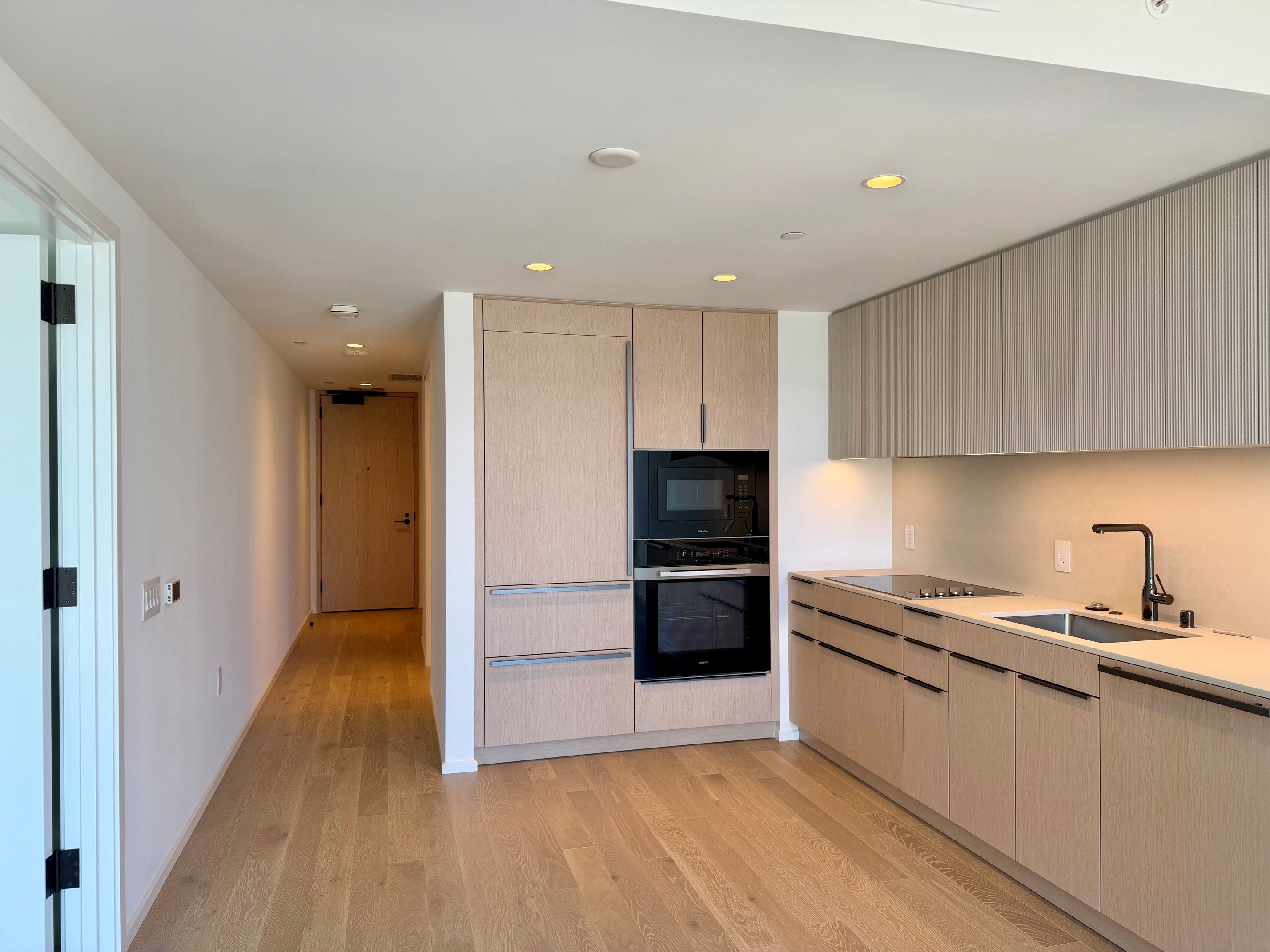 A kitchen with a sink, oven, and cabinets.